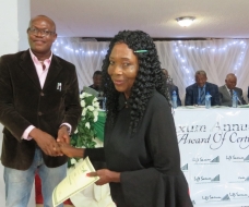 Commissioner for Youth and Sports presenting a certificate to Lady Ebelle Ilo (Honey Lady)
